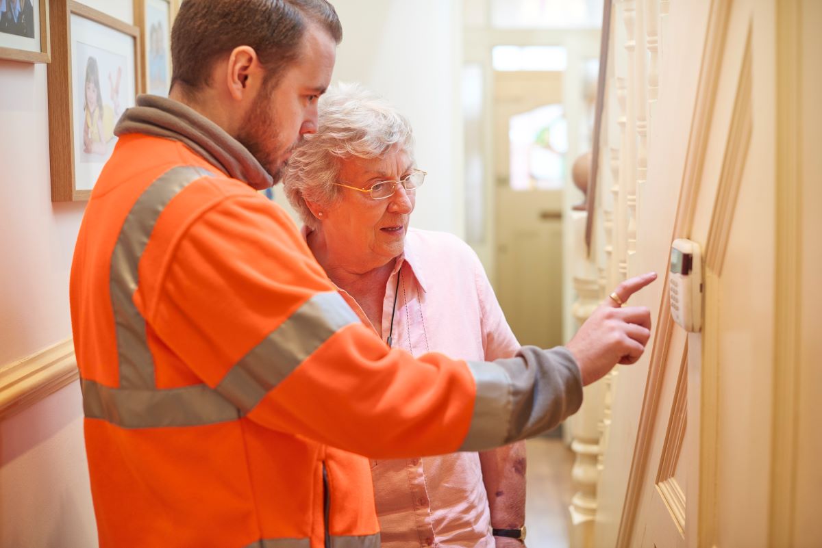 maintenance man showing older lady alarm system